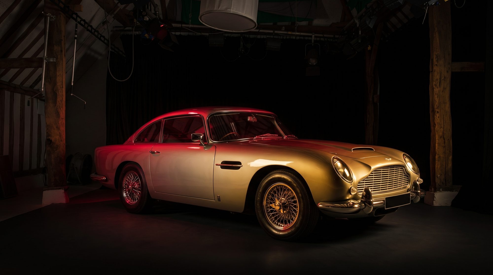 A classic Aston Martin lit gold and red on the studio stage