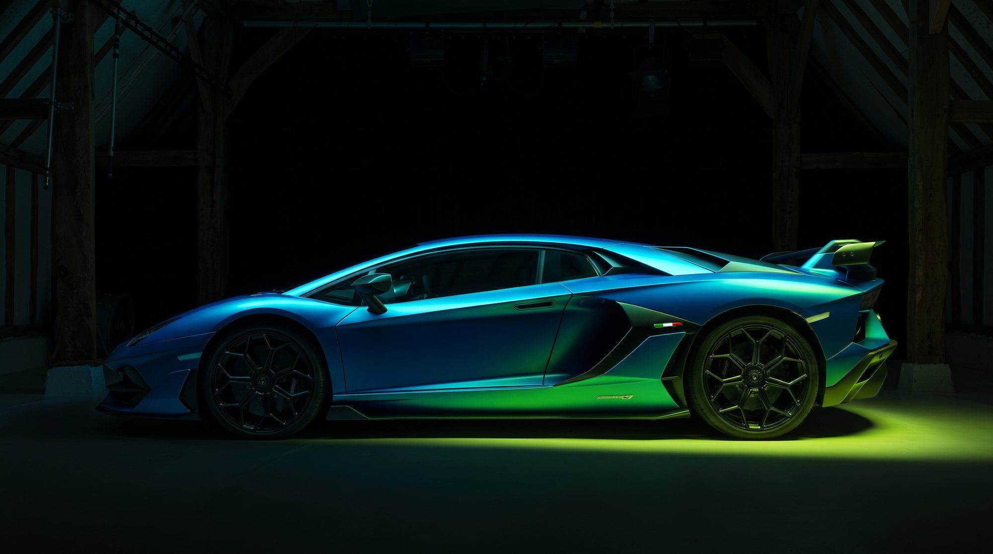 A Lamborghini supercar under blue and green studio lighting on the cove