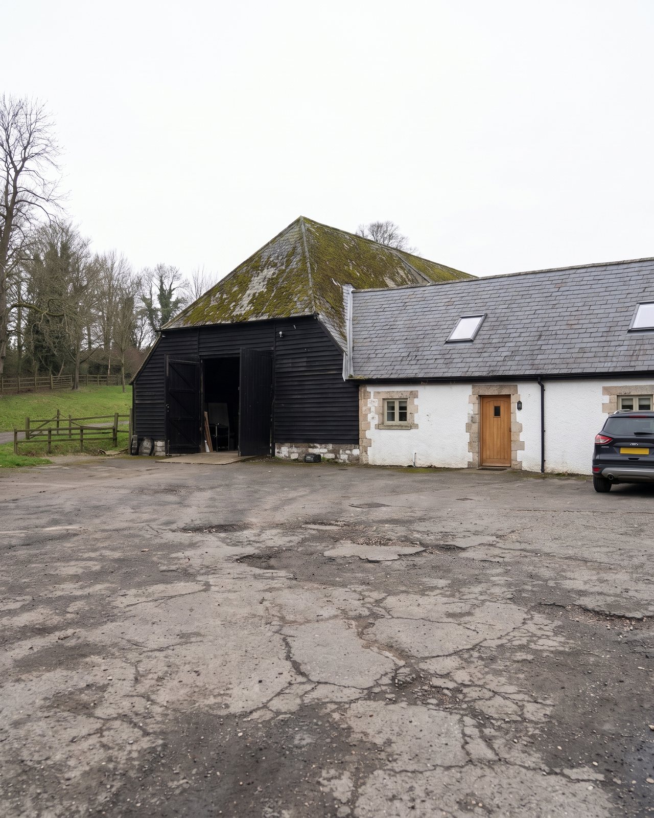 The barn from the car park: black weatherboarded end wall, tall doors and the white office alongside