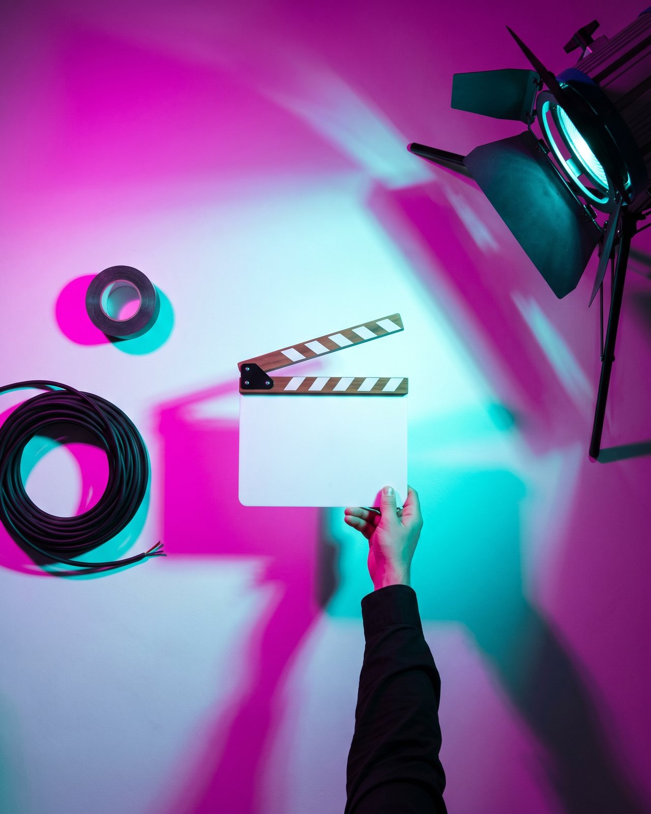 A clapperboard, cable and gaffer tape on the cove floor under magenta and cyan light