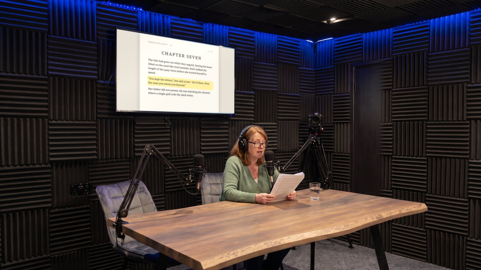 An author recording her audiobook, the manuscript page on the wall screen