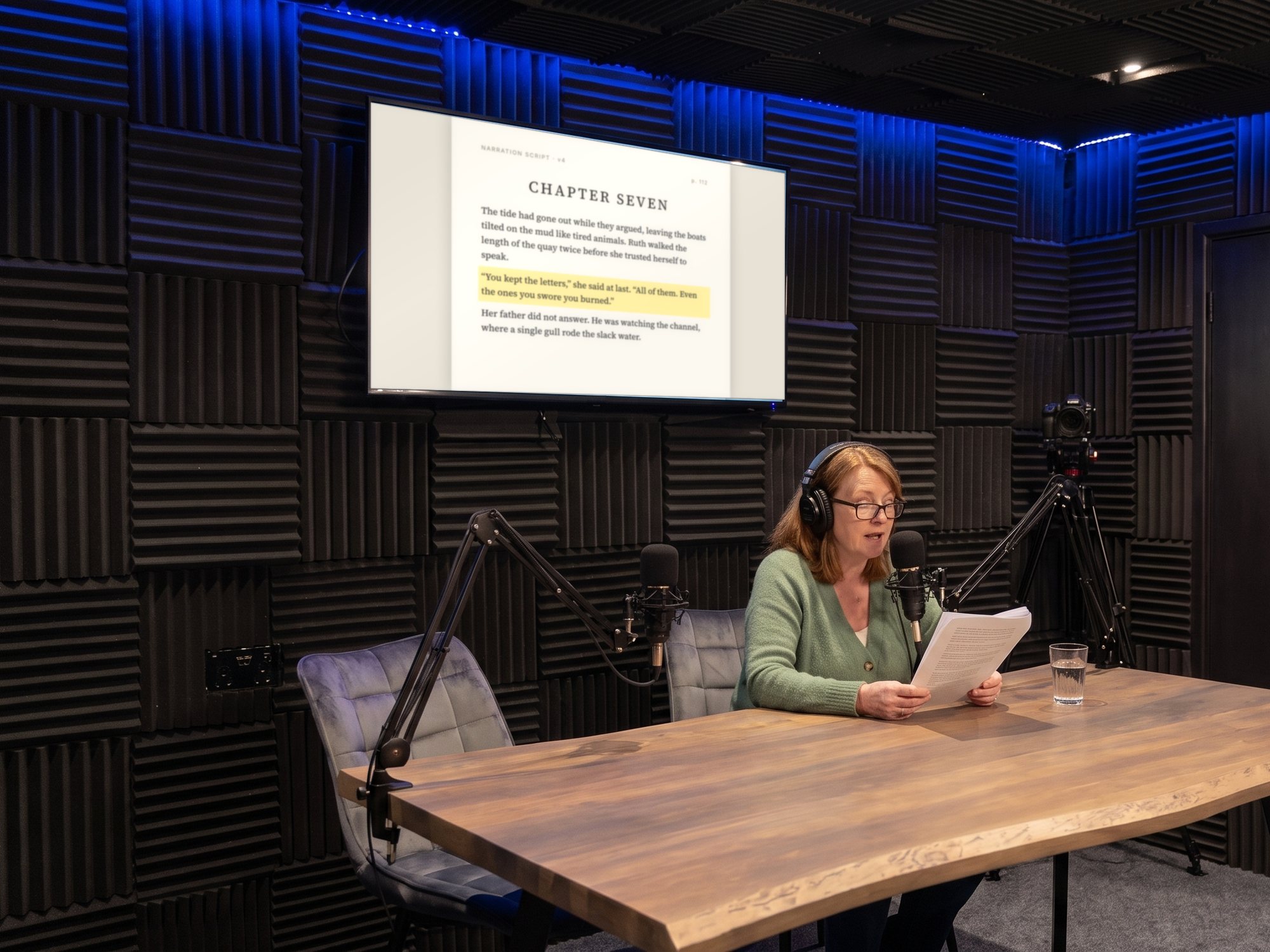 An author recording her audiobook, the manuscript page on the wall screen