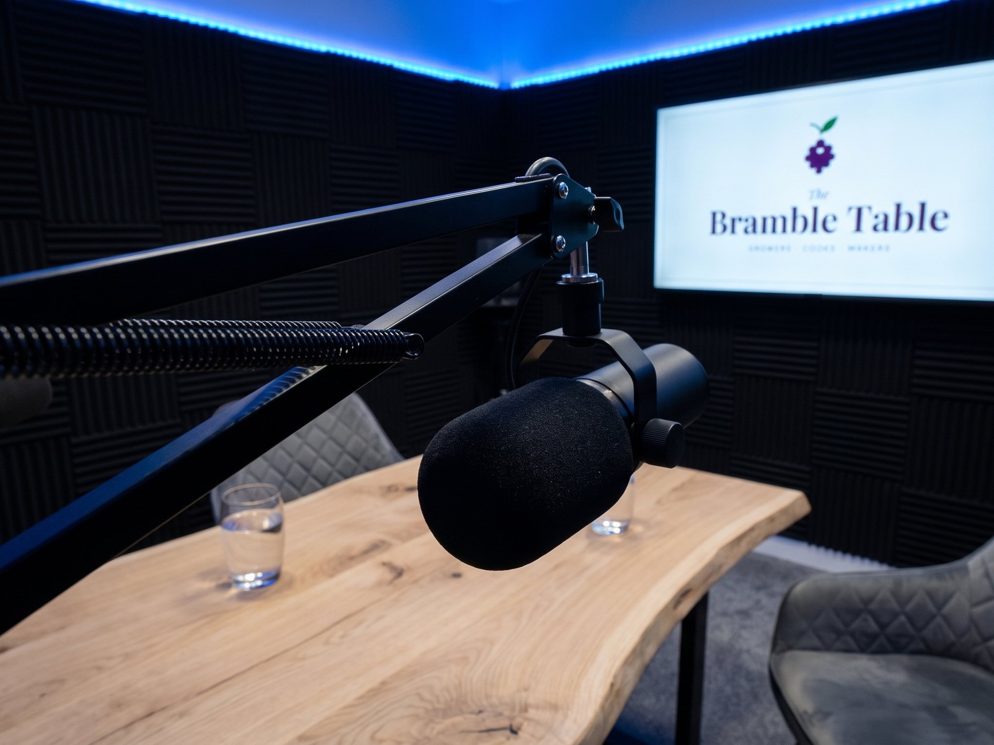 A broadcast microphone on a boom arm over the table, the show card on the screen