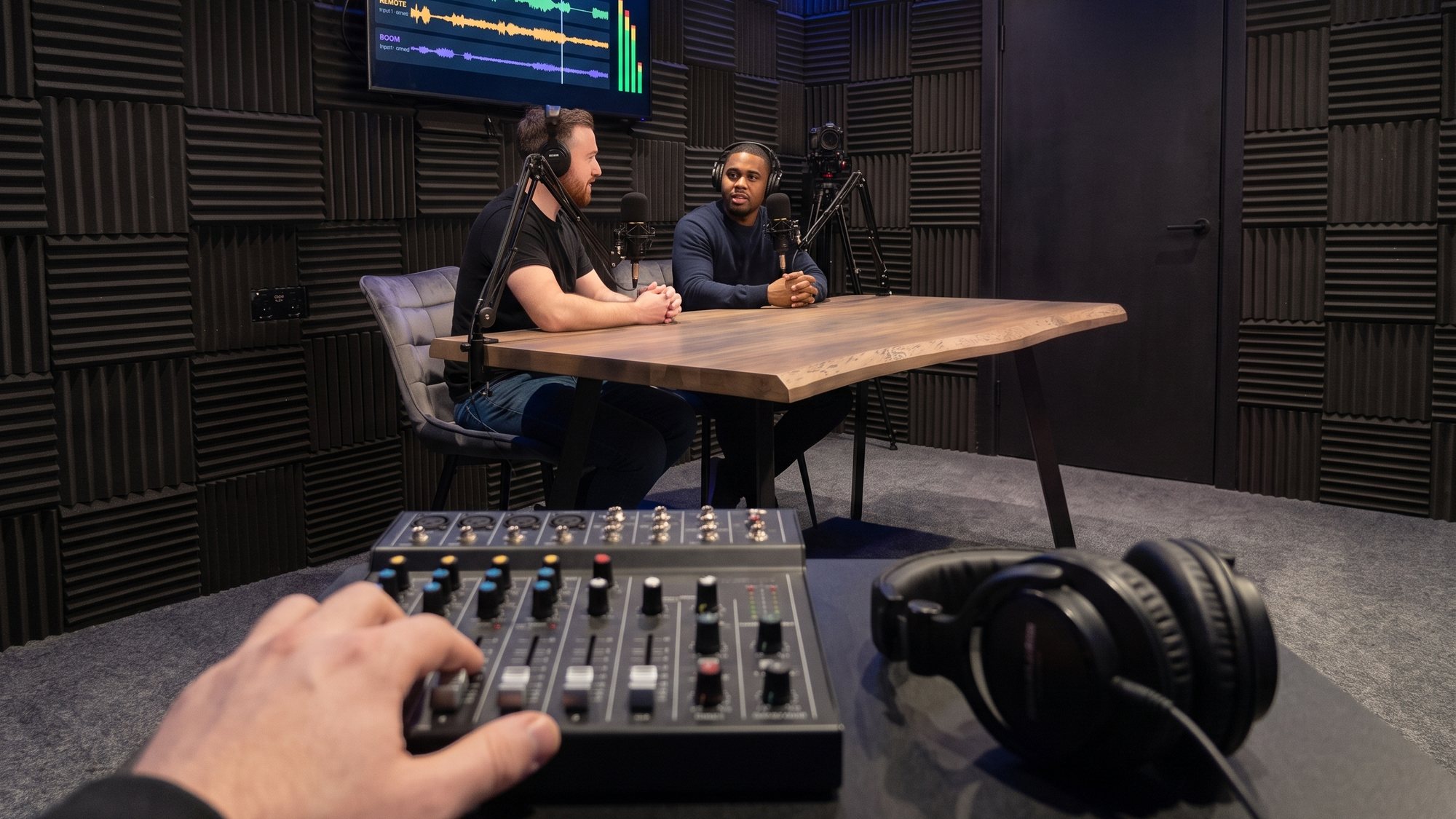 An engineer at the mixer while two guests record at the table