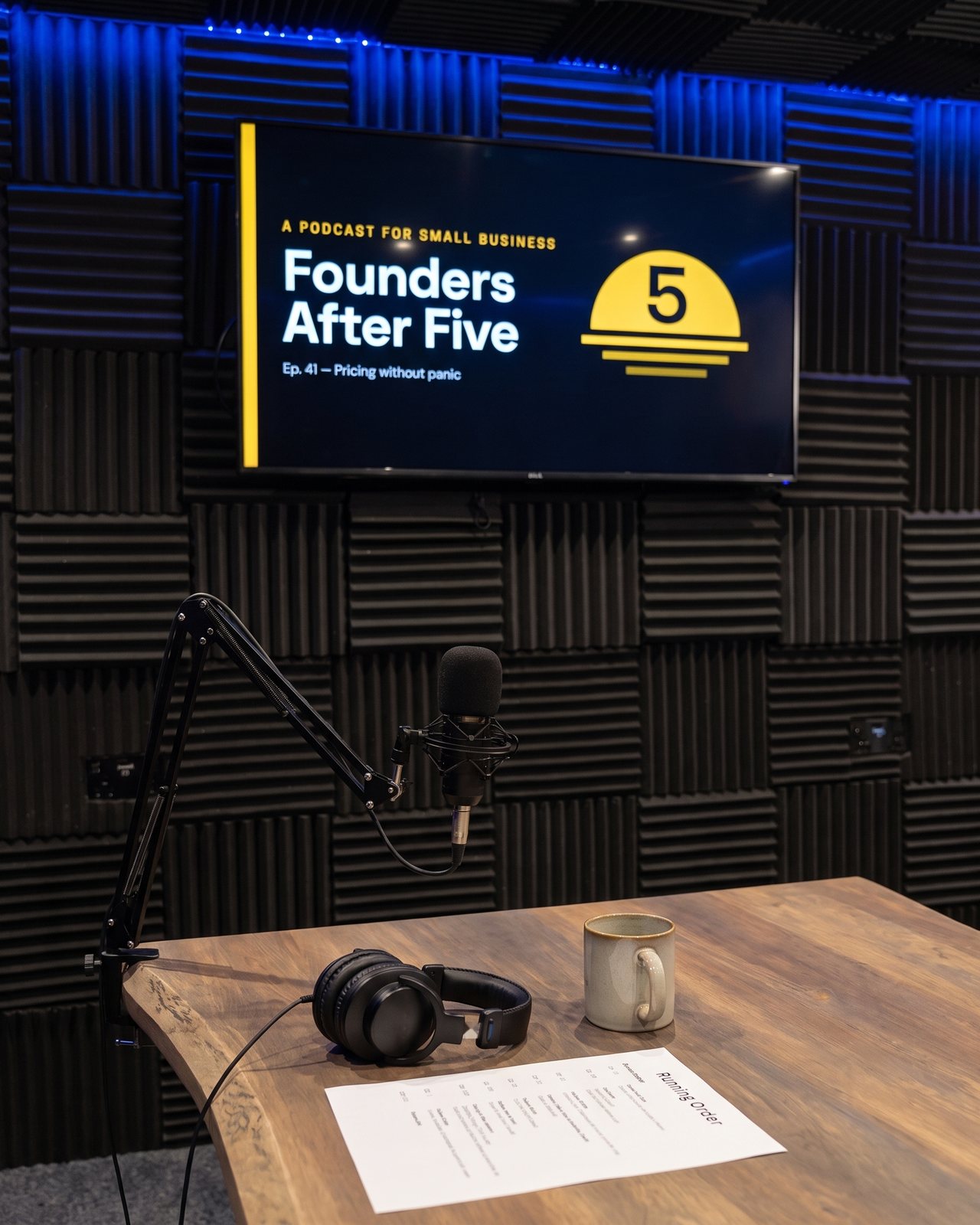 A broadcast microphone on a boom arm over the live-edge table