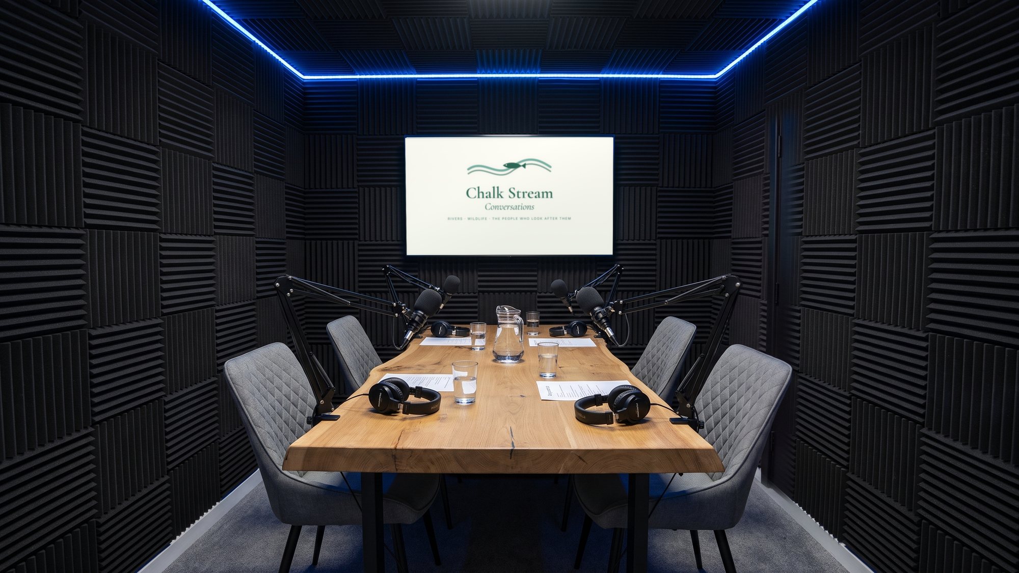 The podcast studio set for a four-person recording, the show card on the screen