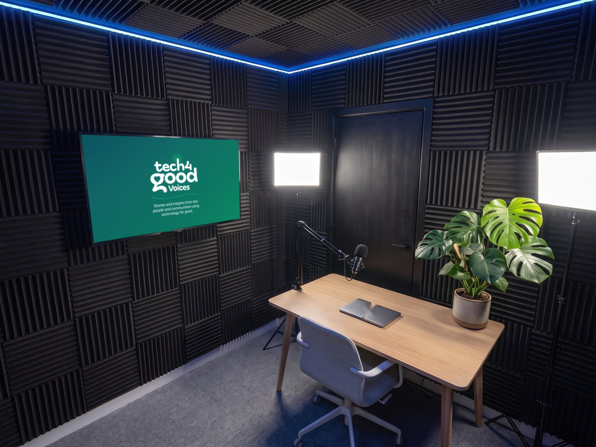 A solo presenter desk with a plant and two LED panels, Tech 4 Good Voices artwork on the screen