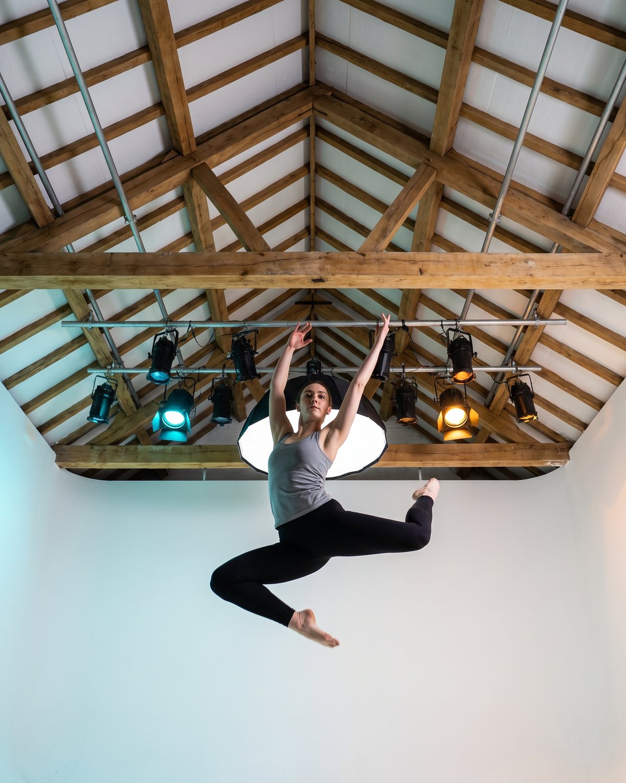 A dancer mid-leap seen from the cove floor, the oak roof and lighting grid above