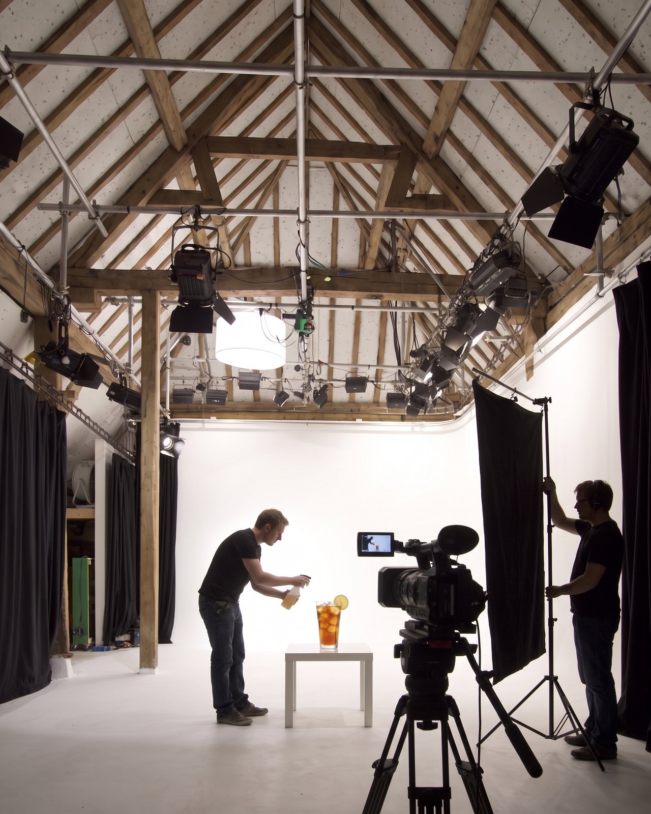 A food stylist misting a glass of iced tea on a tabletop set on the cove