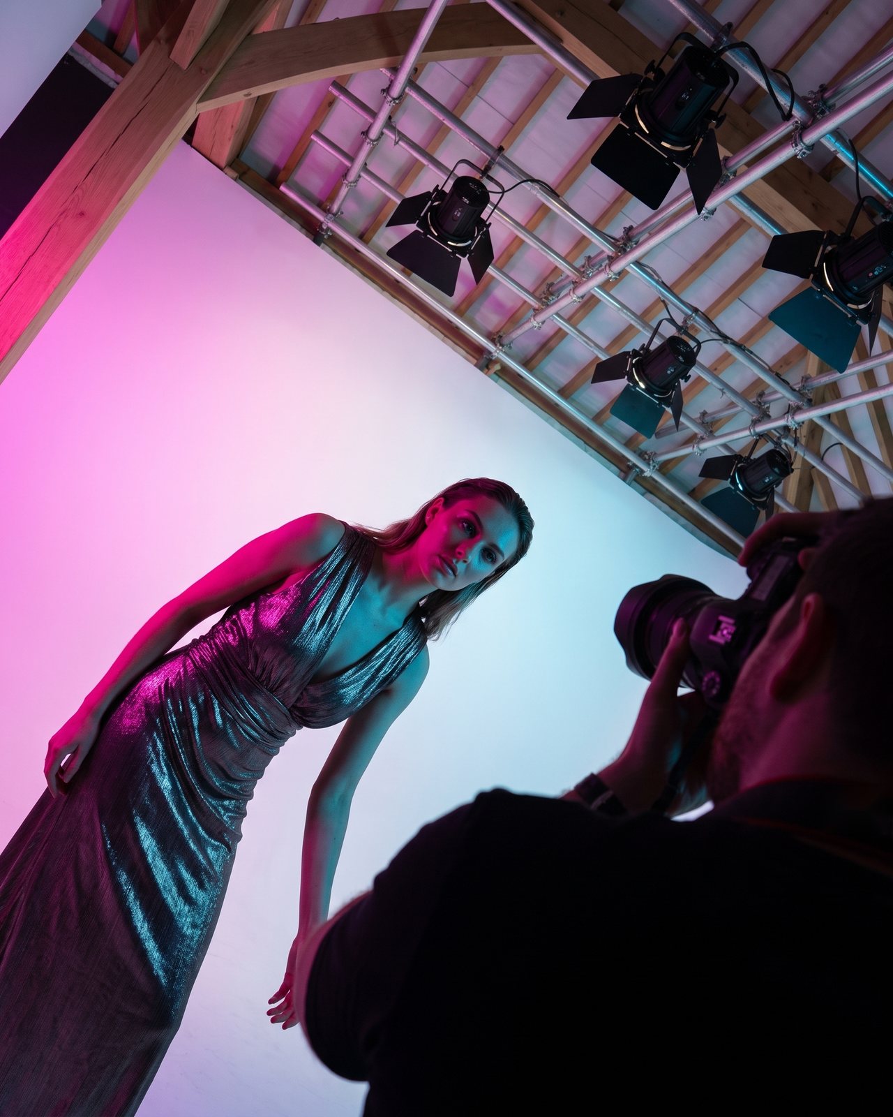 A model in a metallic dress under magenta and cyan light on the cove