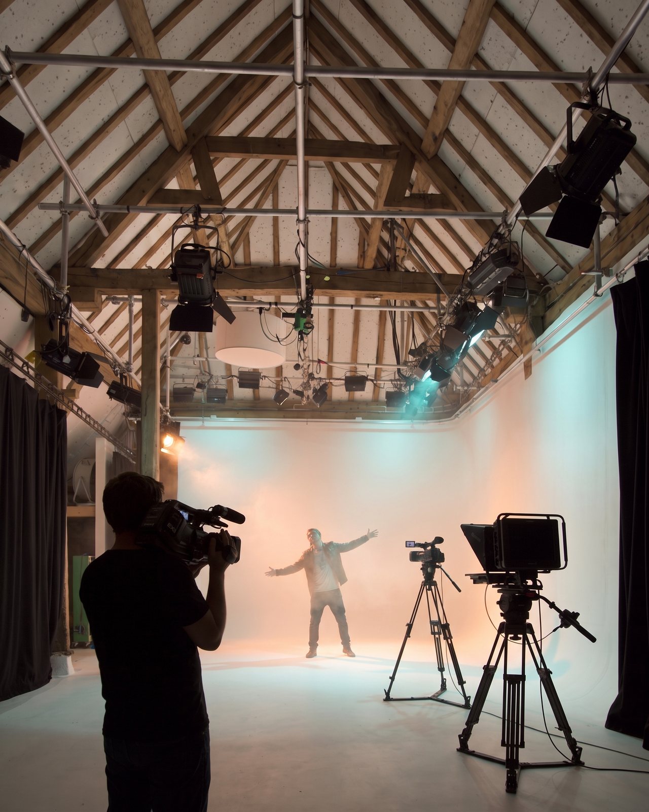 An artist performing on the cove in orange and teal light, a camera operator in silhouette