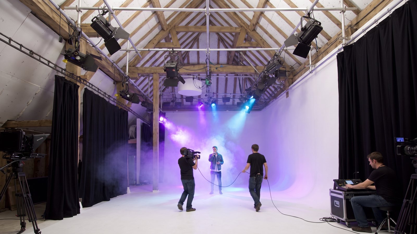 A singer performing in haze on the White Space cove while a camera operator follows