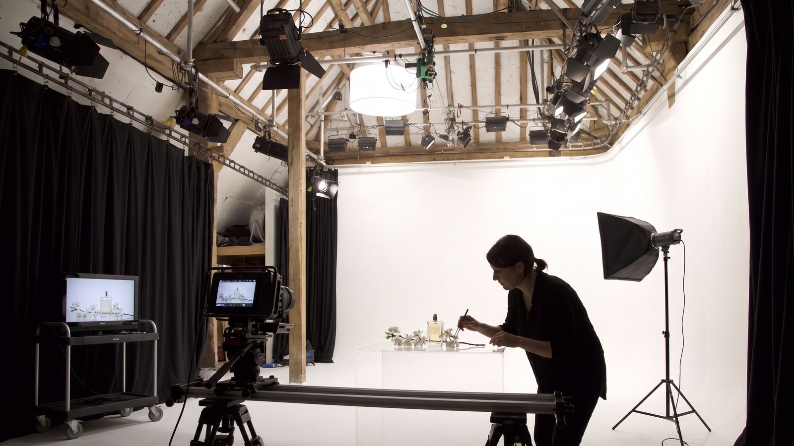A perfume bottle on a plinth framed by a camera on a slider on the cove