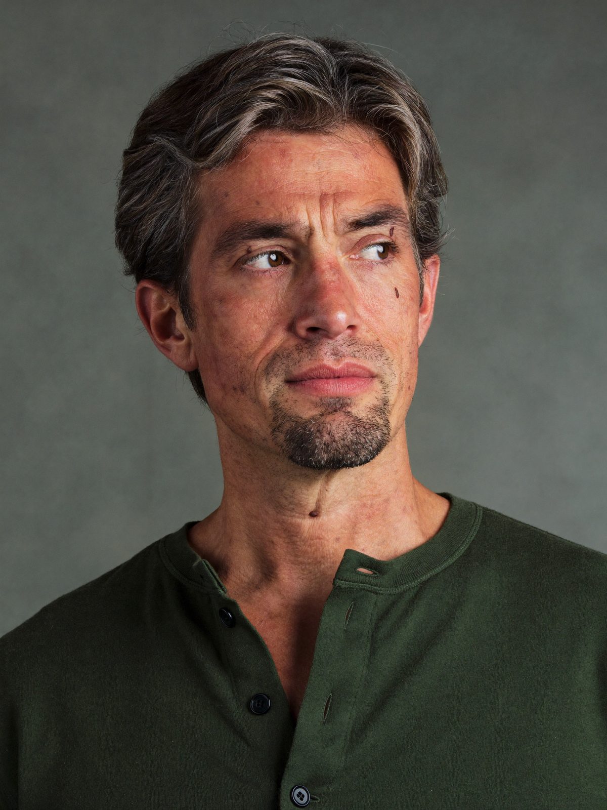 Example actor headshot, a man in his forties with a wry expression on textured grey