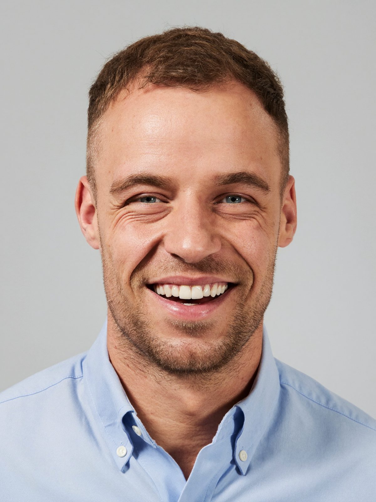 Example LinkedIn headshot, a smiling man in a blue shirt on a pale grey background
