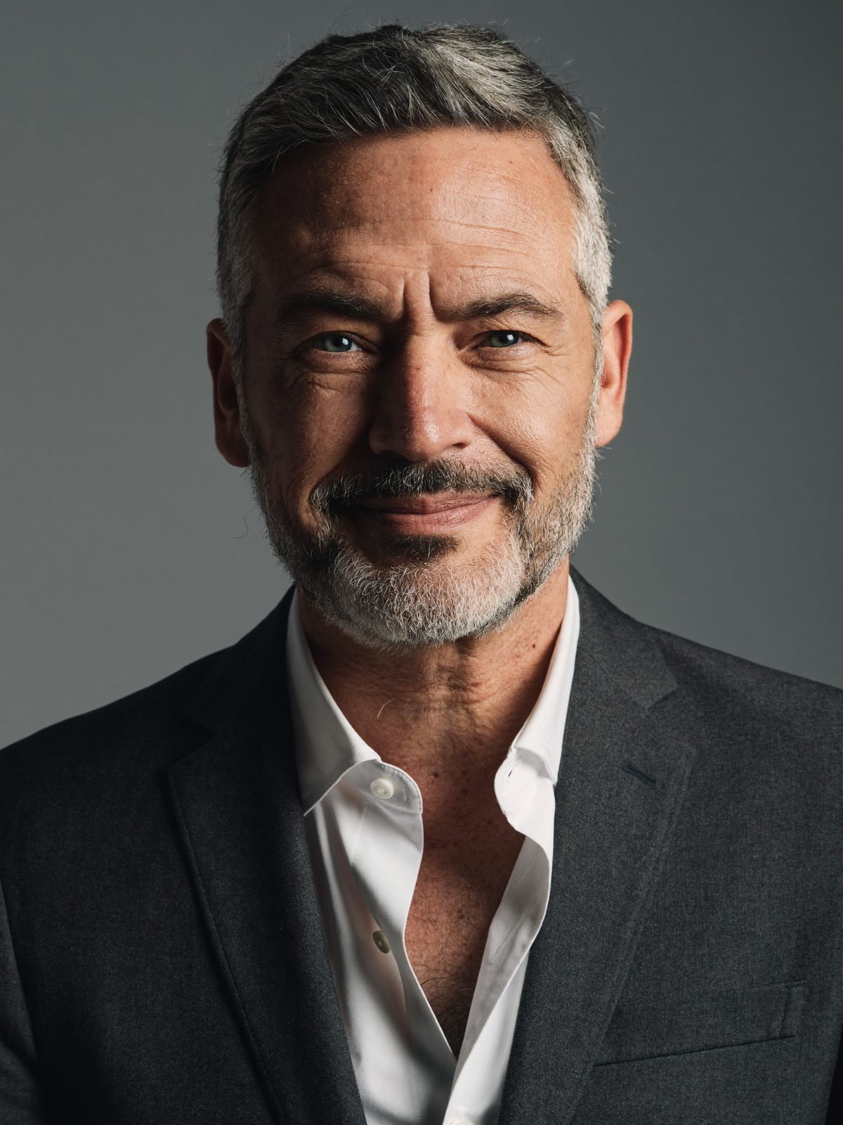 Example headshot, a man with a grey beard in a charcoal jacket on a mid-grey background