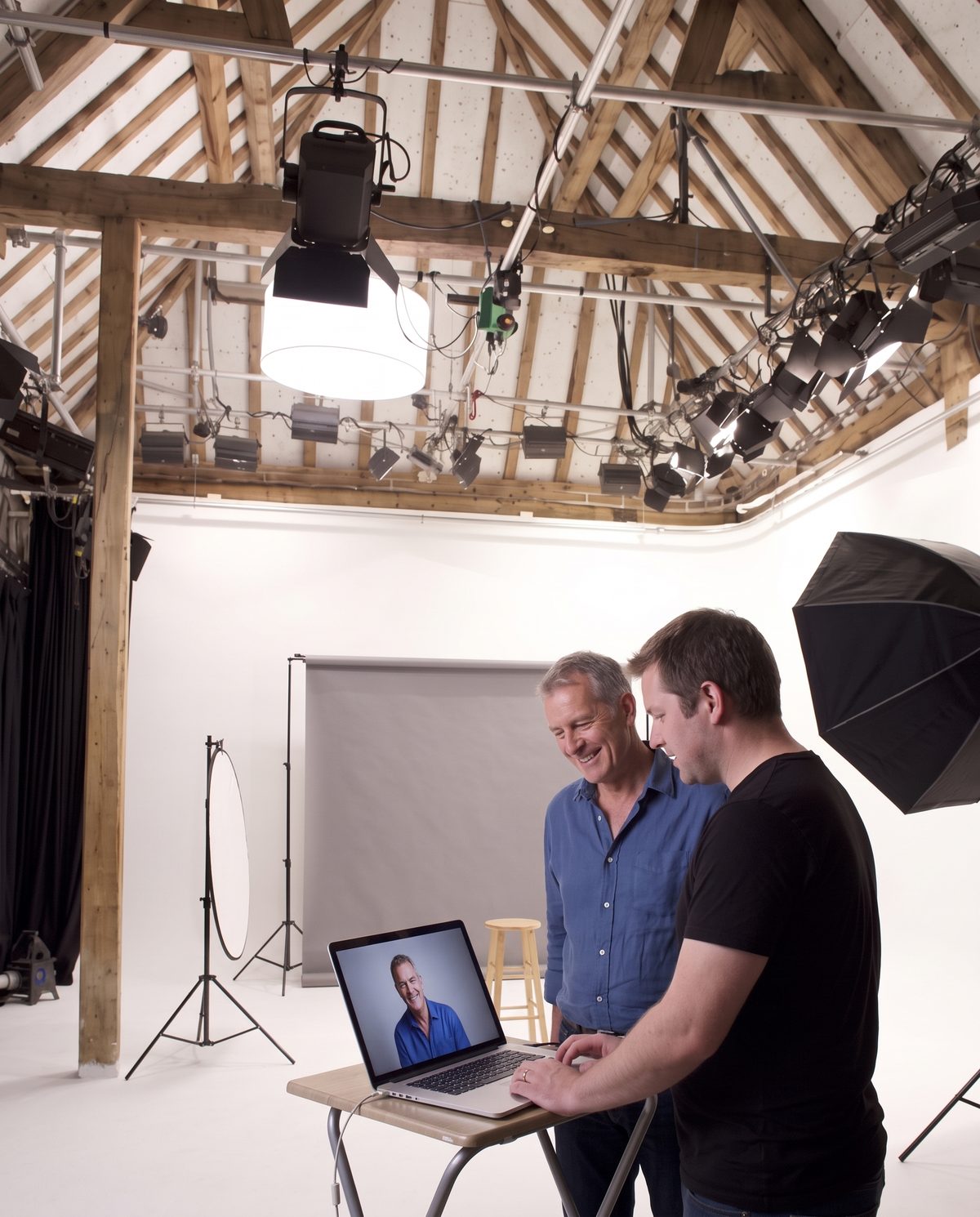 A client and the photographer smiling at his portrait on the laptop screen