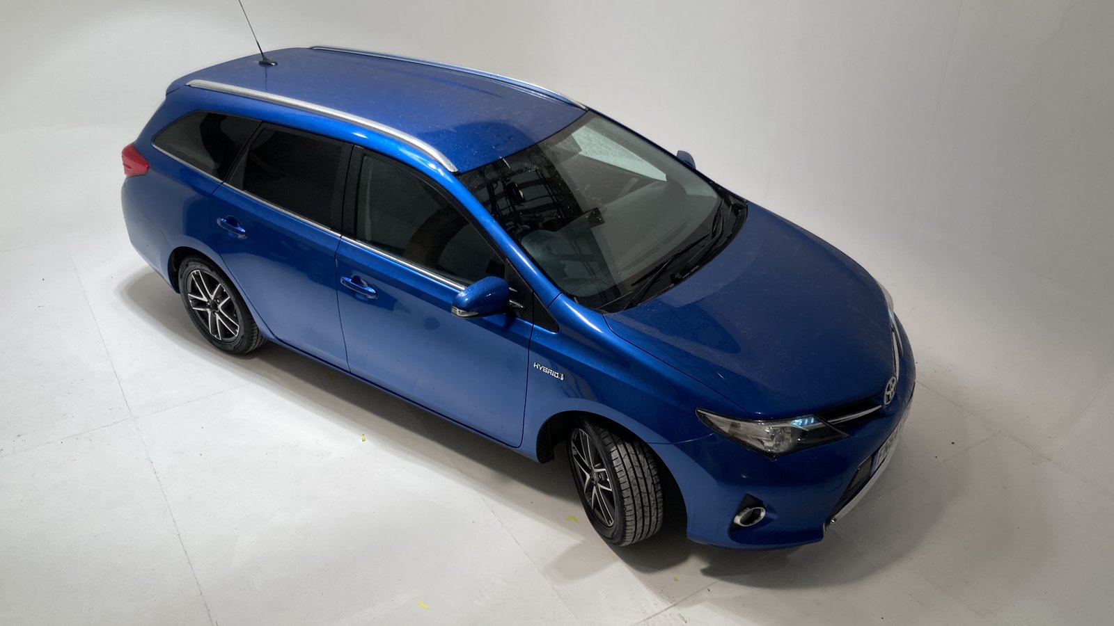 A blue estate car parked on the white infinity cove under the studio grid
