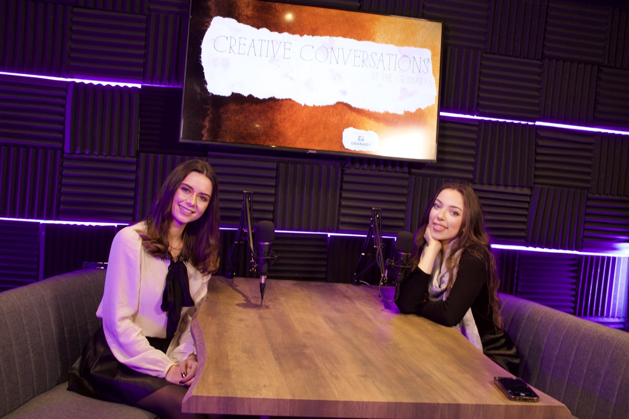 The two hosts of Creative Conversations at the table in the podcast studio