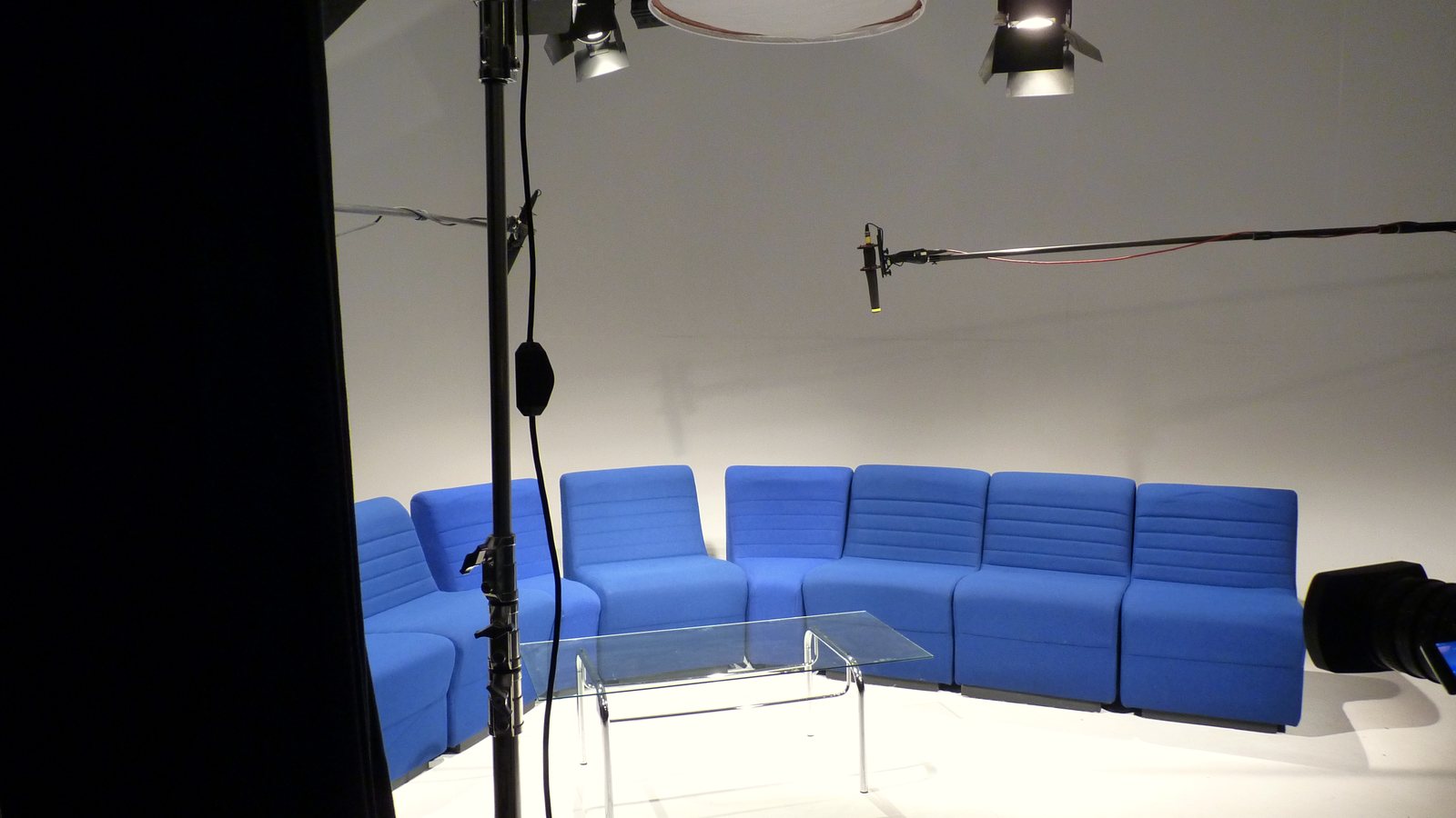 A multi-camera studio set with sofas under the lighting grid