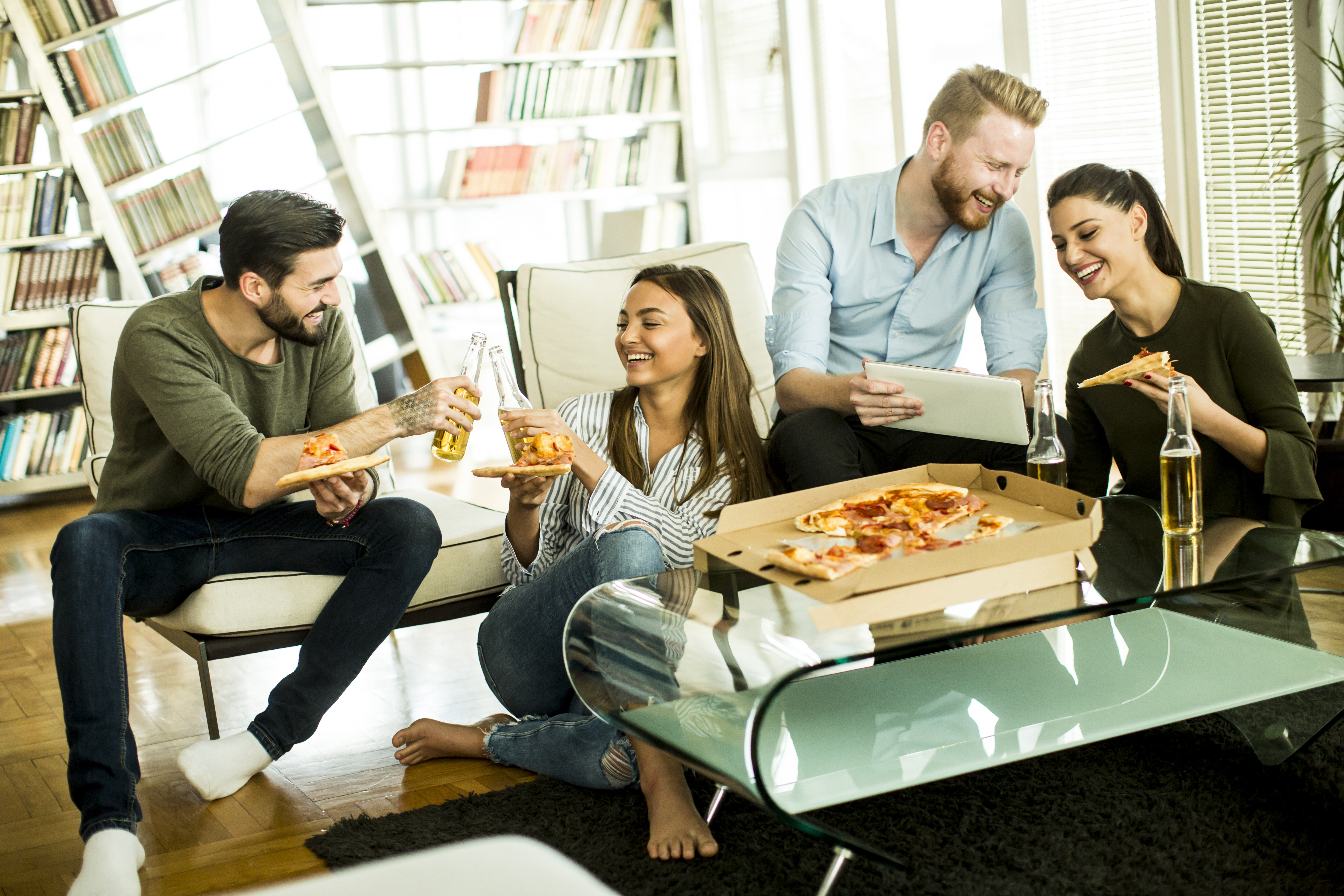 Group of cheerful young people eating pizza in the room and havi People chatting with pizza